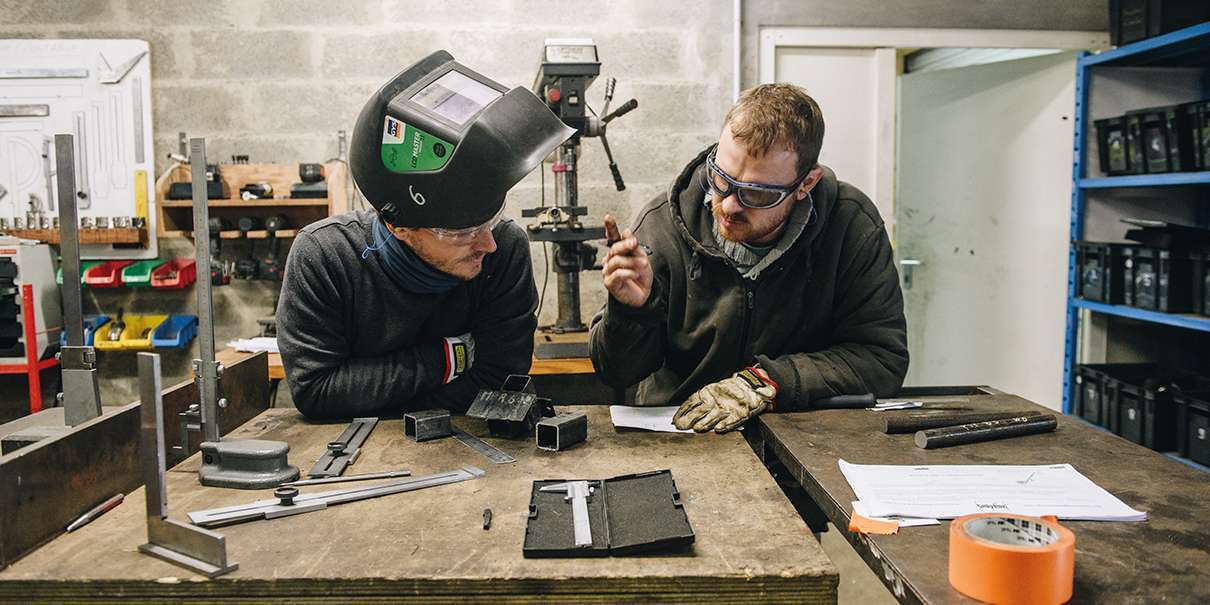 Pierre-Louis et Samuel, tous les deux stagiaires, tentent de retoucher une pièce qui servira au lève-ruche de Samuel, apiculteur en cours d'installation.